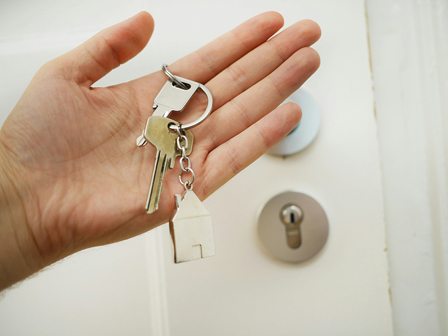 Close-up of house keys in front of a door, symbolizing buying and selling a home in Marquette, MI.
