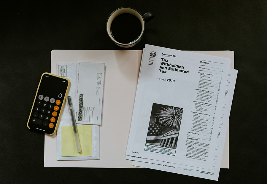 Tax paperwork and calculator on a desk, representing deductions and realtor fees for Marquette, MI home sellers