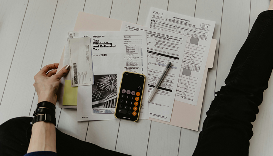 Tax paperwork, calculator, and pen on a desk—understanding capital gains tax when selling a home in Marquette, MI.