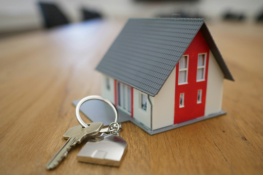 Small model house with a set of keys on a table, symbolizing selling a home fast in Marquette, MI.