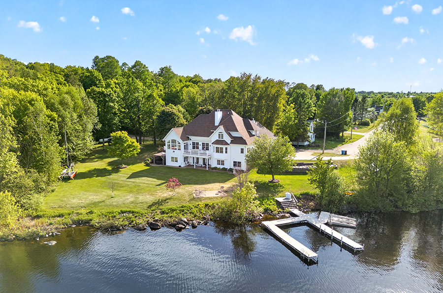Luxury 6-bedroom waterfront home on Lake Michigamme in Michigamme, Michigan, featuring large windows, manicured outdoor spaces, patios, and panoramic lake views.