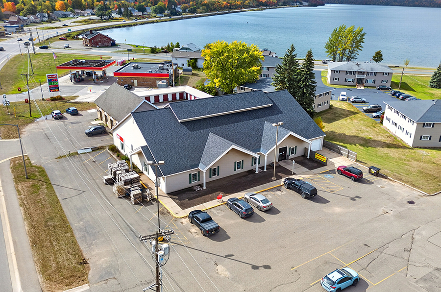Drone view of 390 US-41 E in Negaunee, Michigan, showing the 8,360-square-foot commercial building, paved parking, and US-41 corridor.